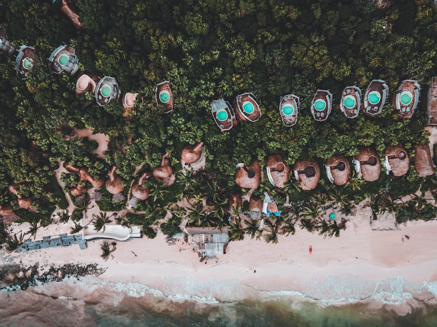 Stunning top-down view of a tropical beach resort with private pools and lush greenery.